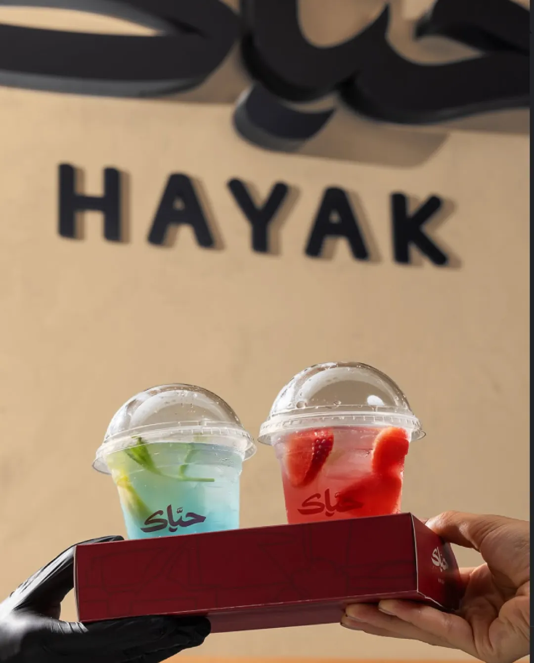 Two Hayak drinks handed across the counter under the HAYAK sign
