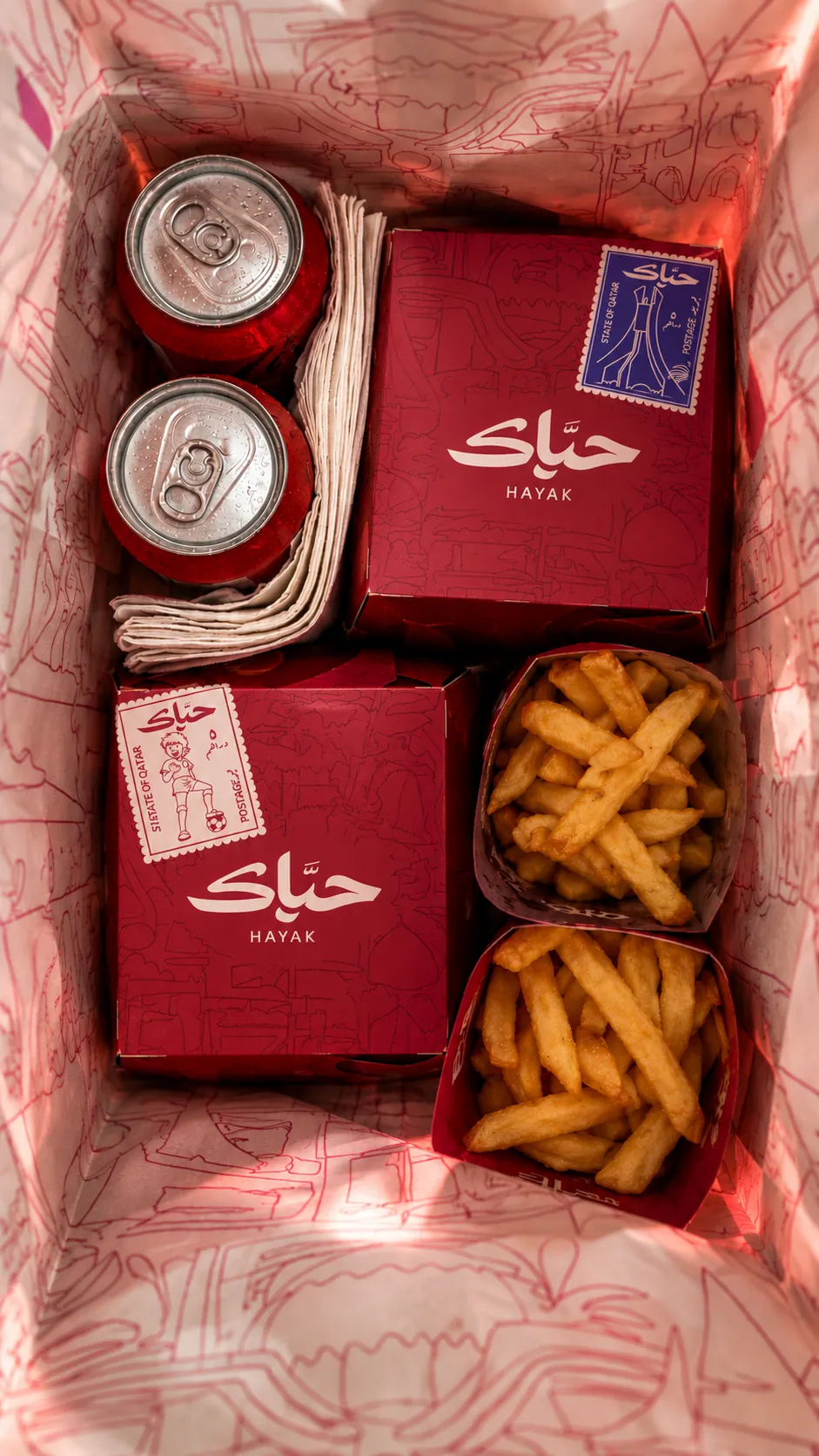 A Hayak takeaway bag opened to show boxes, fries and drinks