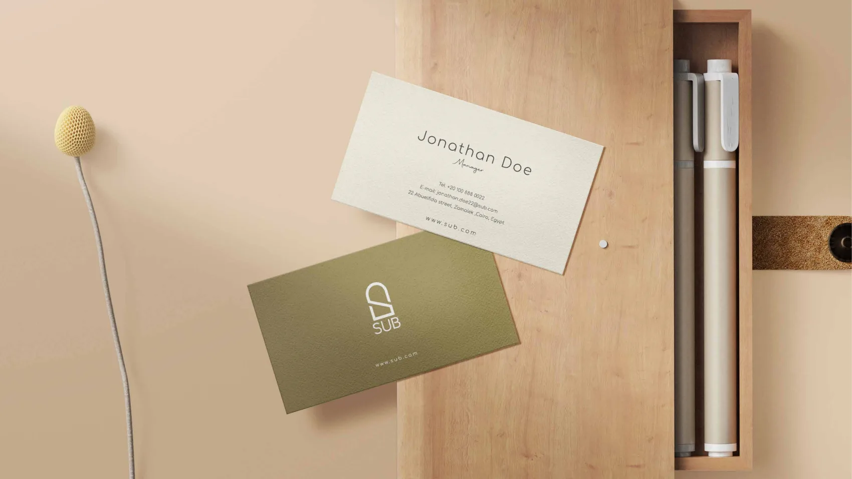 SUB business cards, olive and cream, resting on a wooden surface