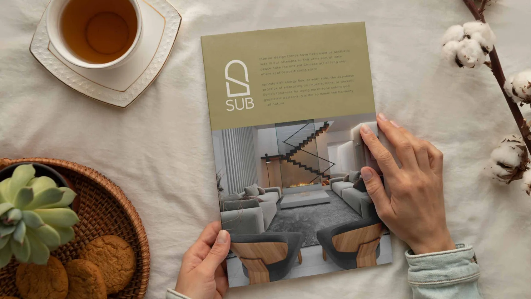 A SUB catalogue held in two hands, its gold cover showing the mark above an interior render